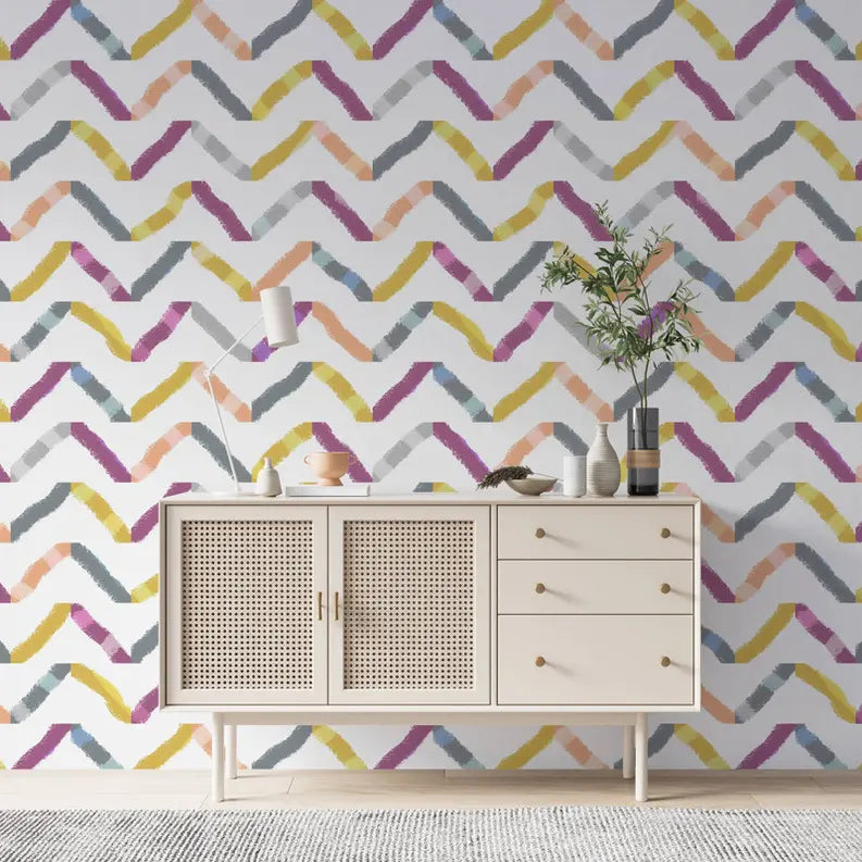 Multicolor zigzag patterned wallpaper with pastel hues, paired with a modern, white wooden sideboard and decorative plants.
