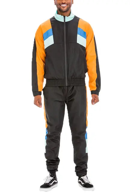 Men's black windbreaker tracksuit with orange, blue, and mint color blocks, featuring a zip-up jacket and matching pants.