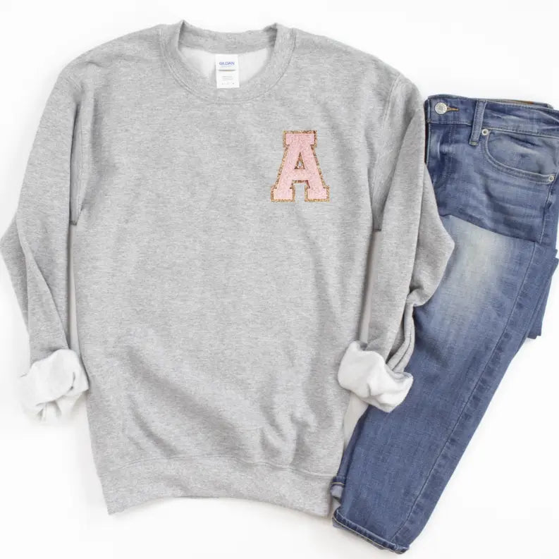 Gray sweatshirt with pink glitter "A" patch, paired with light-wash denim jeans, perfect casual wear.