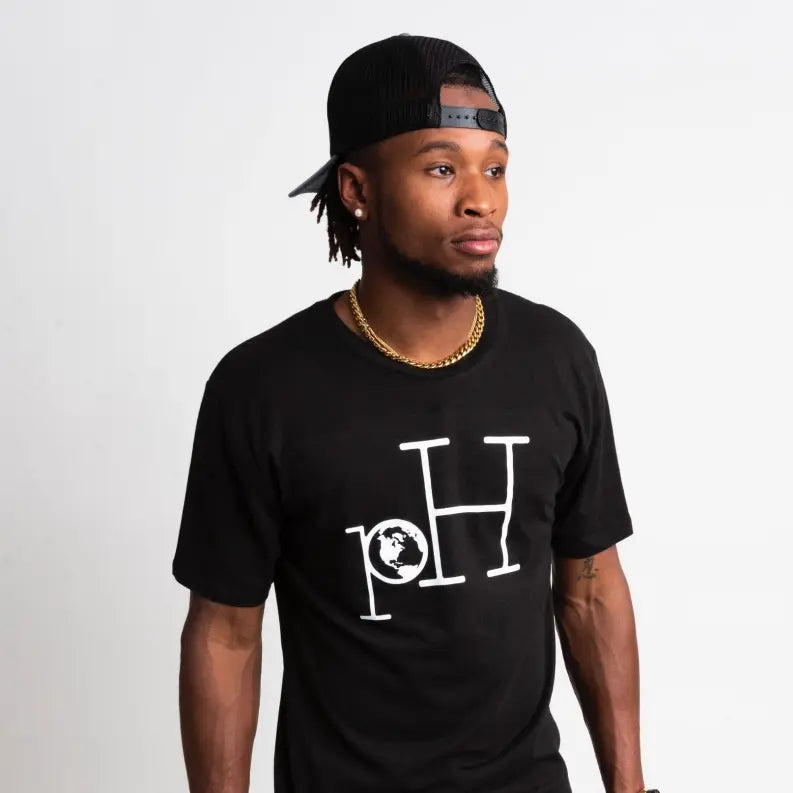 Men's black graphic t-shirt featuring white "pH" logo and globe design, styled with a black snapback hat.